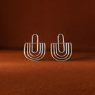 Pair of silver hoop earrings on a brown background