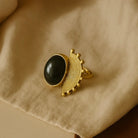 Gold ring with a black gemstone on a beige fabric background