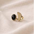 Gold ring with black gemstone on a beige fabric background
