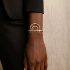 Gold bracelet on a wrist with a neutral background