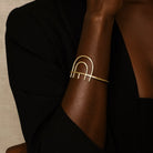 Gold bracelet on a person's wrist with a neutral background