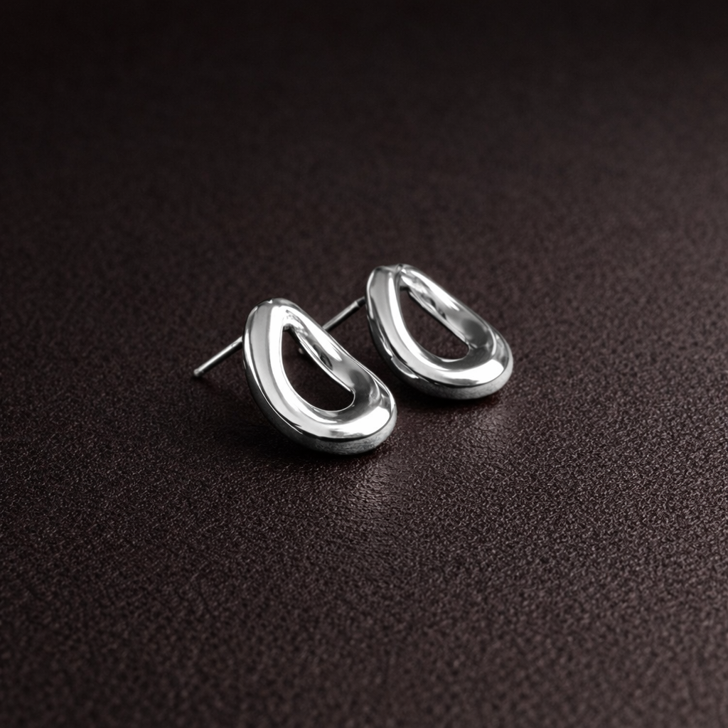 Pair of silver earrings on a dark brown surface