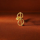 Gold ring with a unique design on a brown fabric background