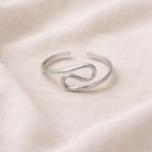 Silver ring with a unique design on a beige fabric background