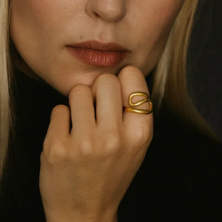 Close-up of a woman's hand with a gold ring on her finger against a dark background