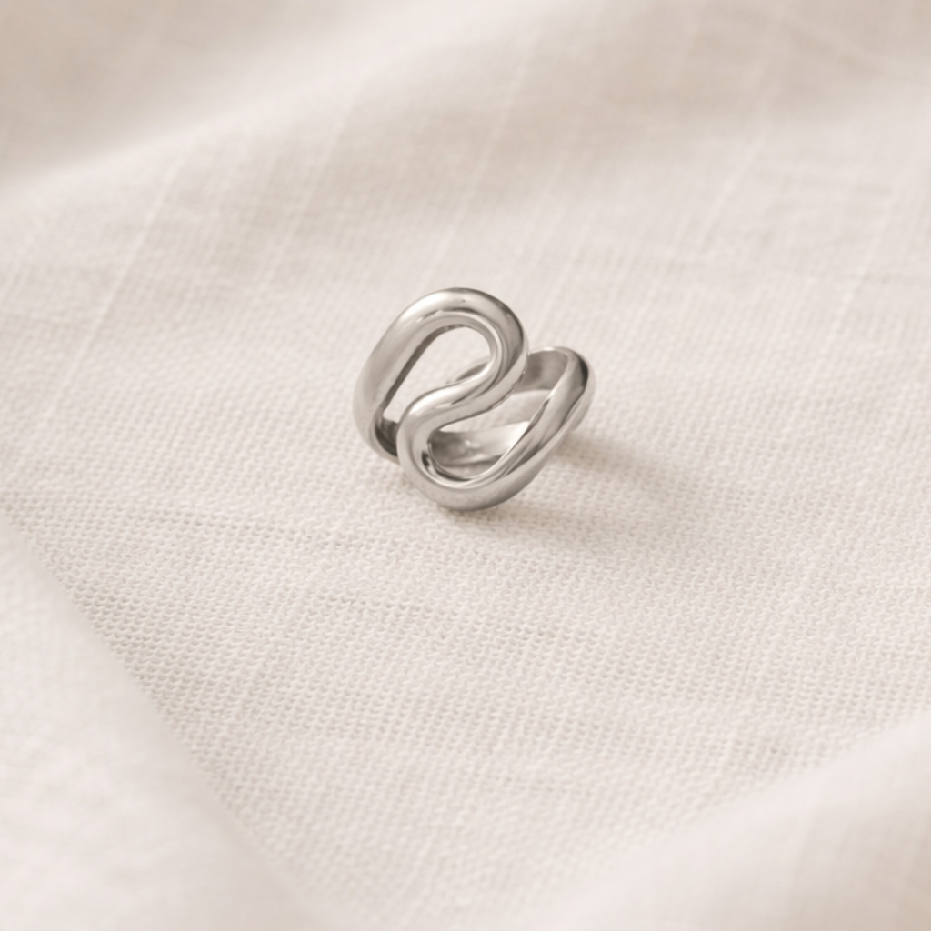 Silver ring with a unique design on a white fabric background