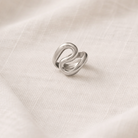 Silver ring with a unique design on a white fabric background