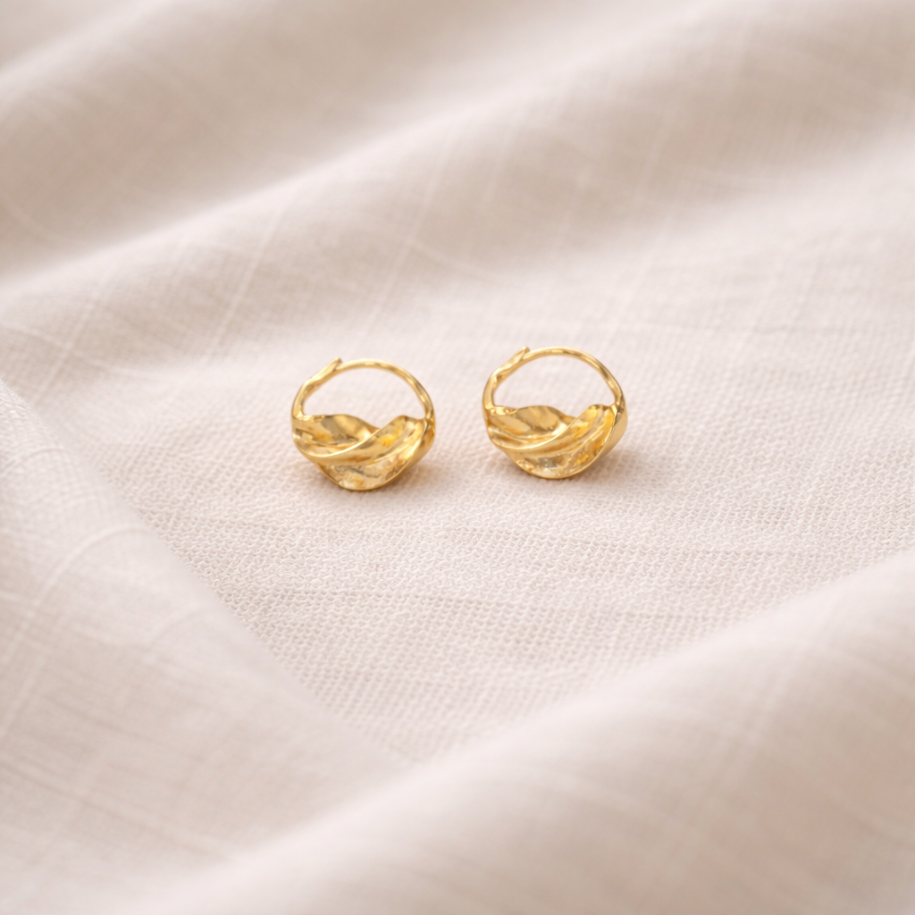 Gold hoop earrings on a beige fabric background