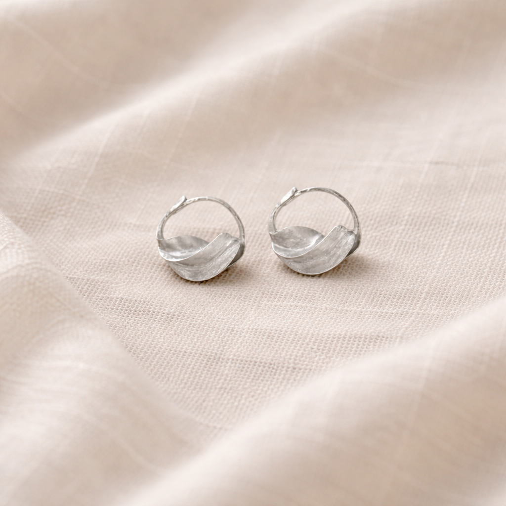Silver hoop earrings on a beige fabric background
