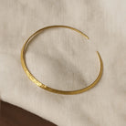 Gold bracelet on a beige fabric background