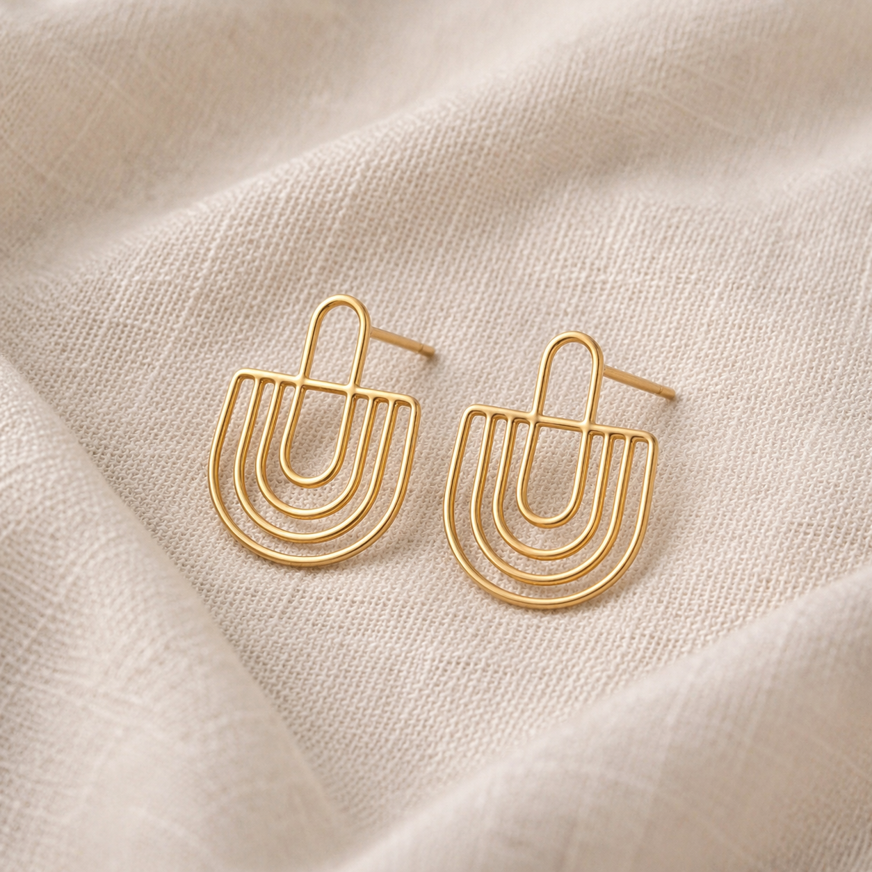 Gold earrings on a beige fabric background