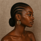 Woman with braided hair wearing gold earrings against a beige background