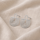 Silver earrings on a beige fabric background