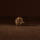 Bronze face pendant on a dark brown background