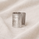 Silver cuff bracelet with elephant design on a beige fabric background