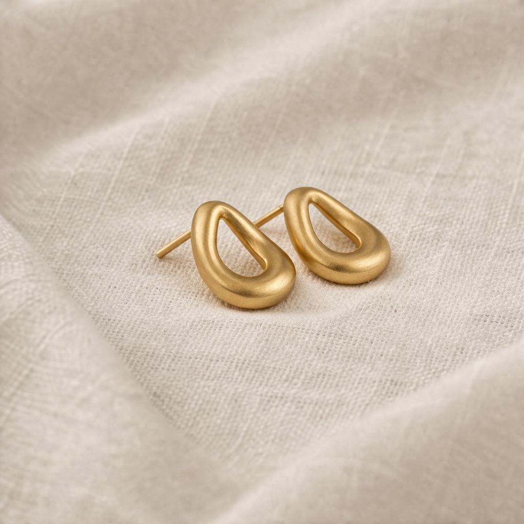 Gold hoop earrings on a beige fabric background
