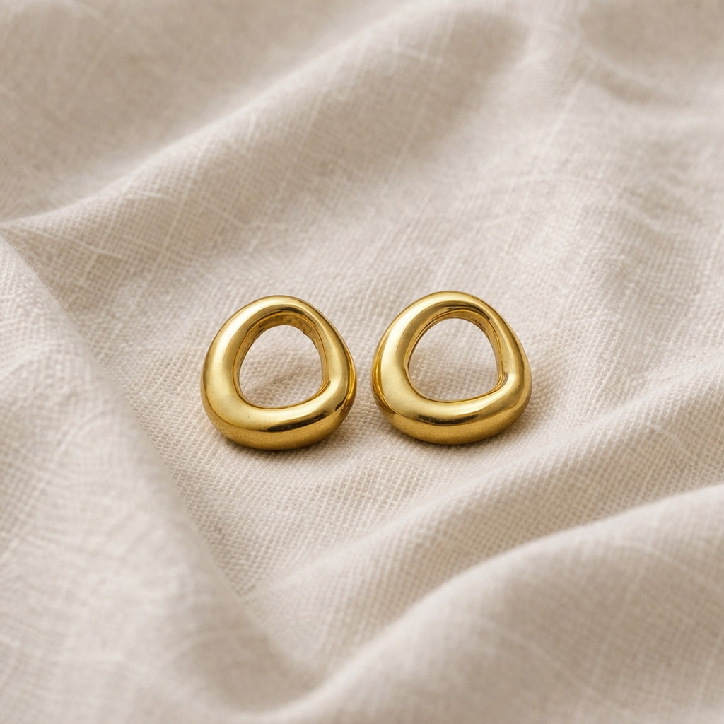 Gold earrings on a beige fabric background