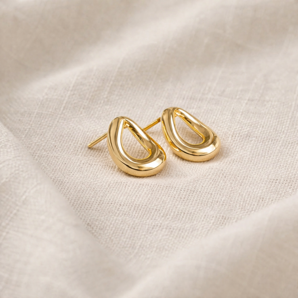 Gold earrings on a beige fabric background