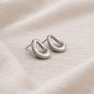 Silver hoop earrings on a beige fabric background